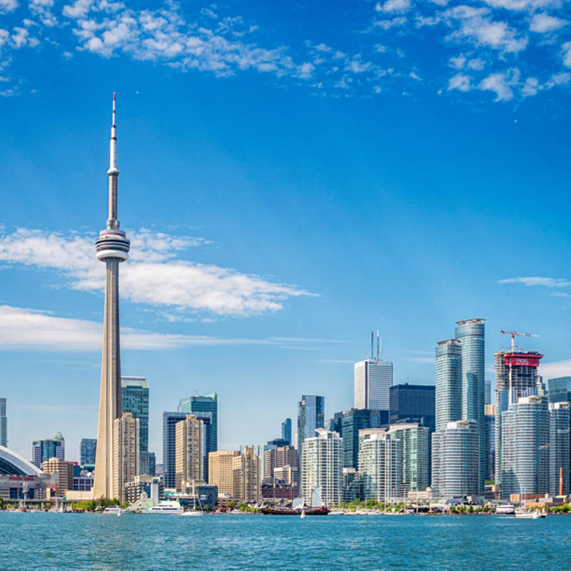 a city skyline with a tall tower and a body of water