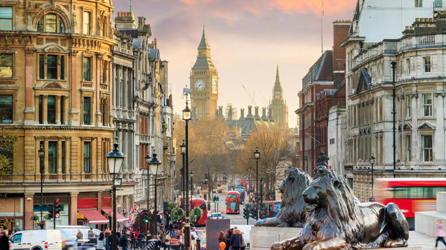 a city street with statues of lions and people walking around
