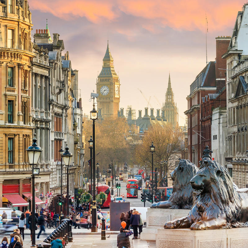 una calle de la ciudad con estatuas de leones y gente caminando