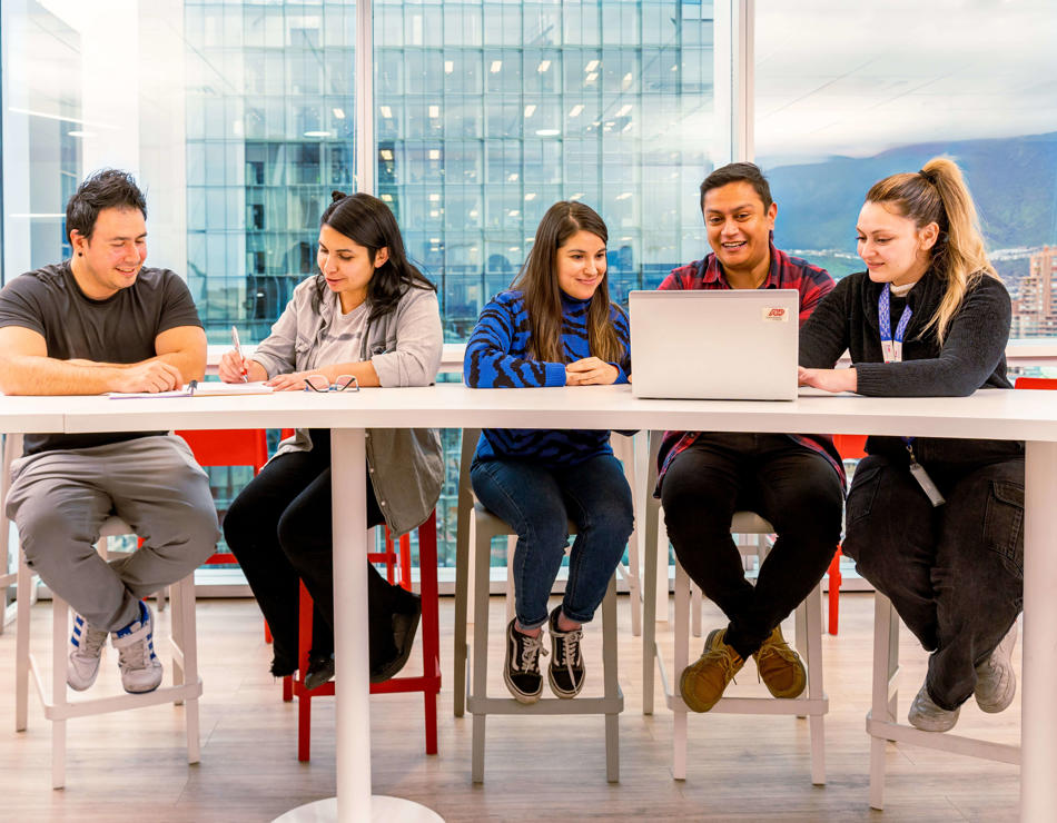 un groupe de personnes assises à des tables avec des ordinateurs portables