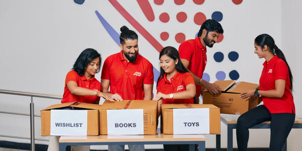 un groupe de personnes en chemises rouges debout autour d’une table avec des boîtes