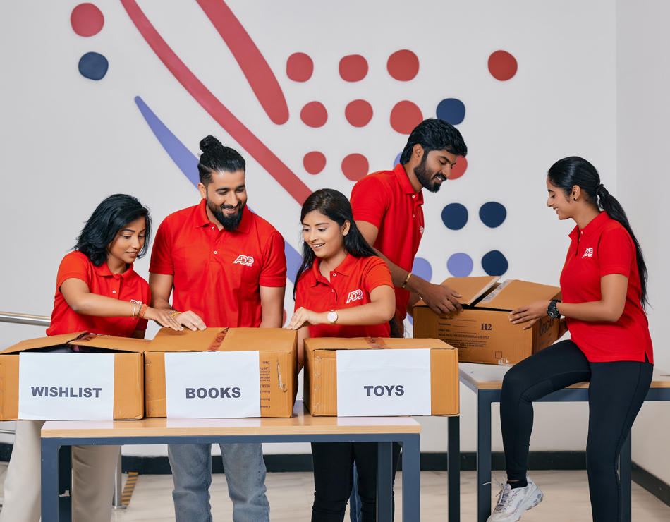 Un grupo de personas con camisas rojas de pie alrededor de una mesa con cajas