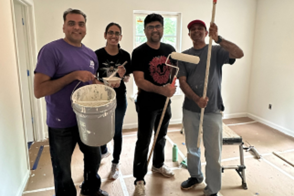 Un grupo de personas sosteniendo rodillos de pintura y cubos